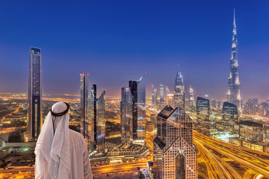 Arabian man watching night cityscape of Dubai with modern futuri